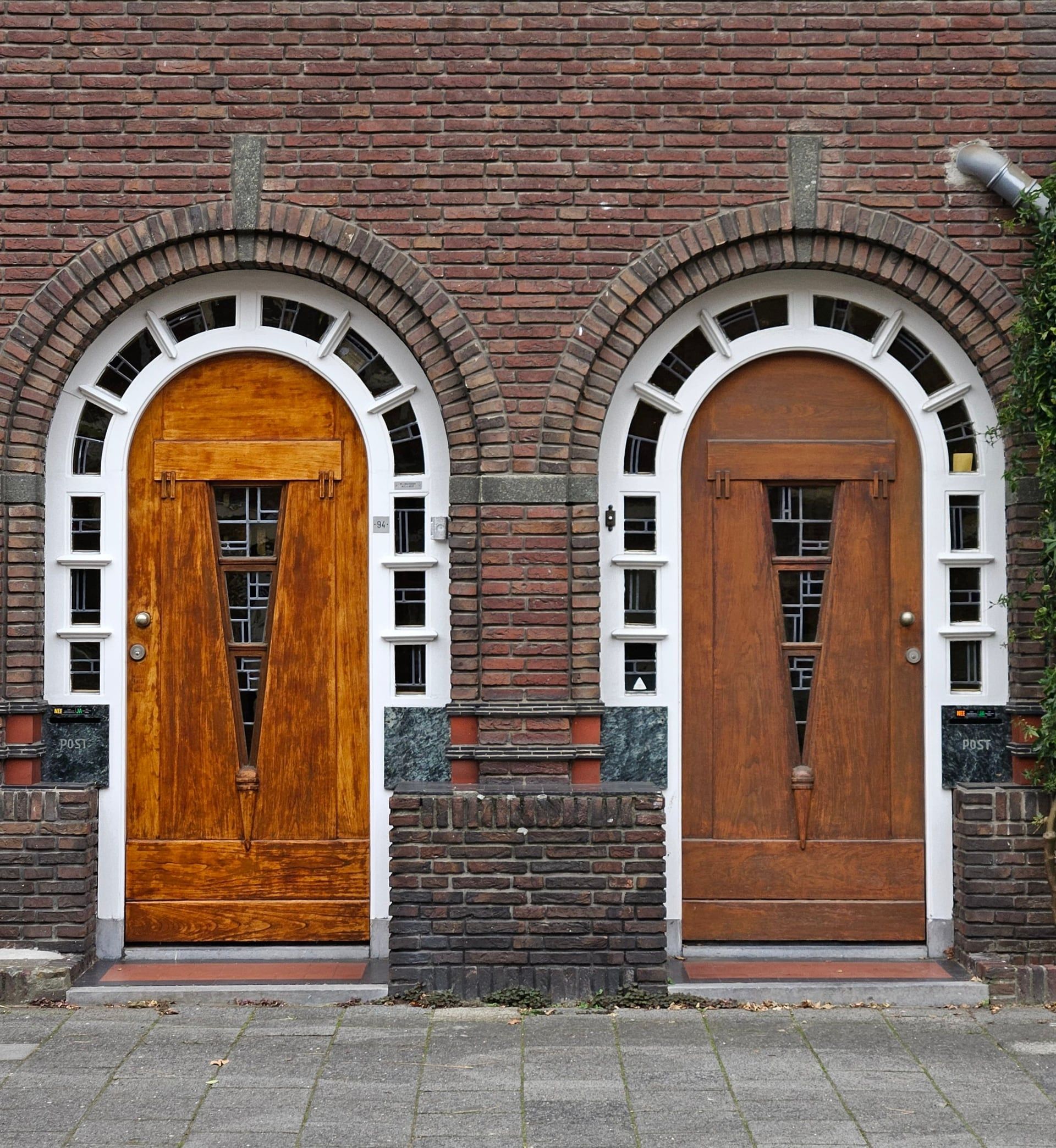 Twee gevernist houten boogdeuren in een bakstenen gevel
