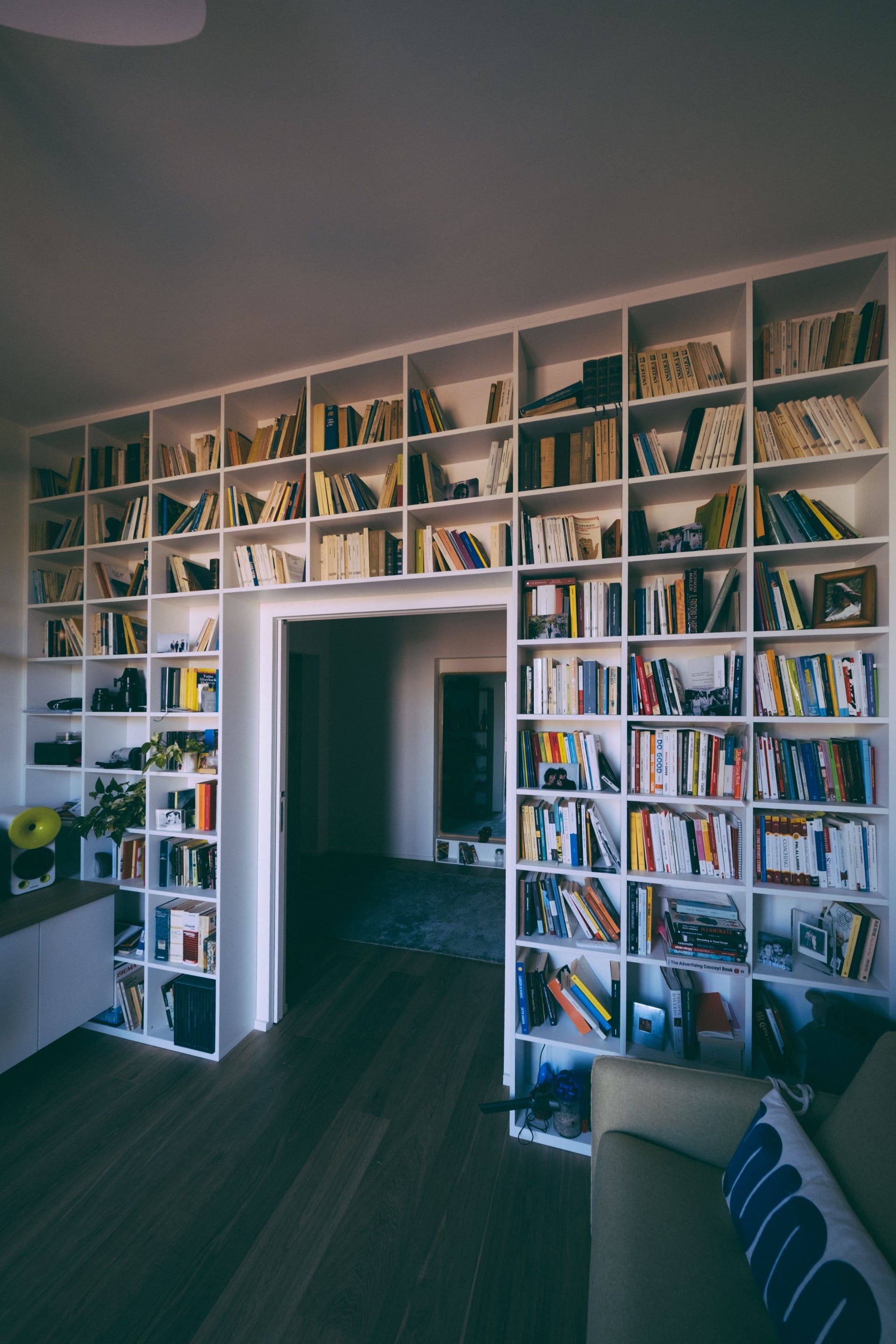 Witte boekenkast van vloer tot plafond rond een deuropening